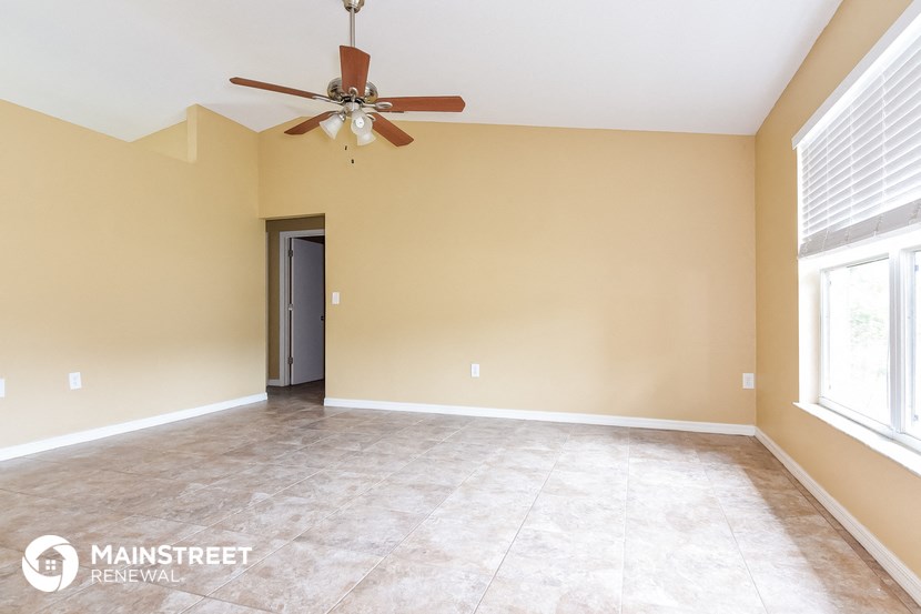 the spacious living room with ceiling fan and tile flooring