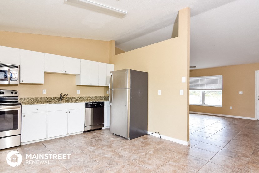 a kitchen with white cabinets and a stainless steel refrigerator