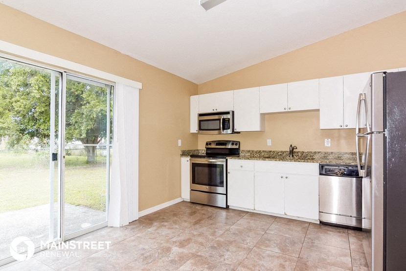 a kitchen with white cabinets and stainless steel appliances and a sliding glass door