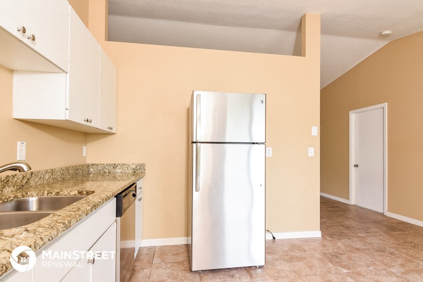a kitchen with white cabinets and a stainless steel refrigerator
