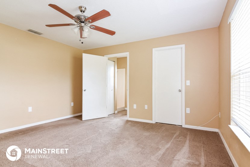 a living room with carpet and a ceiling fan