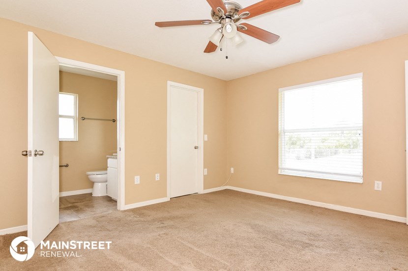 the master bedroom has a carpeted floor and a ceiling fan