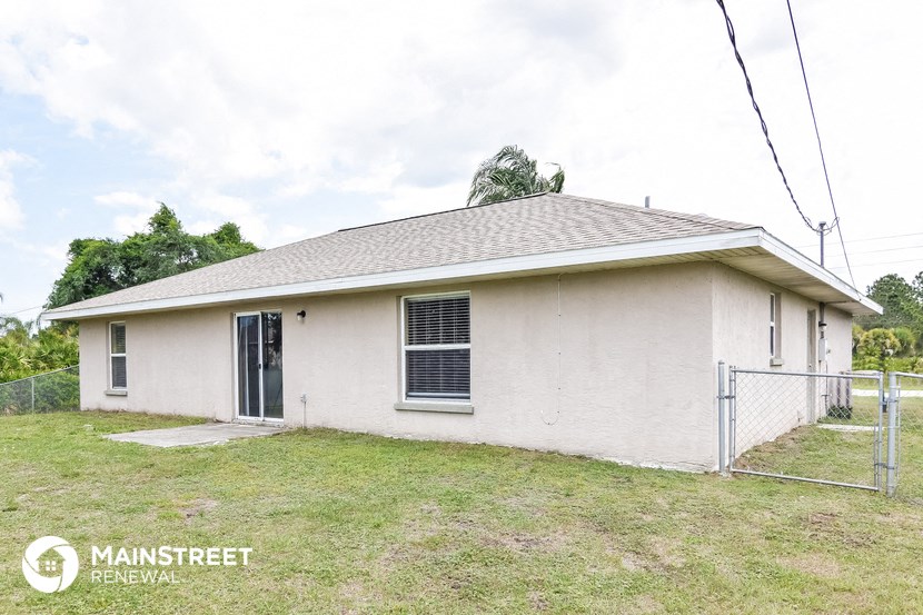 the front of a white house with a fenced in yard