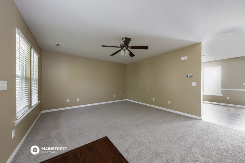an empty living room with a ceiling fan