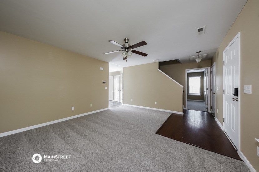 a living room with carpet and a ceiling fan