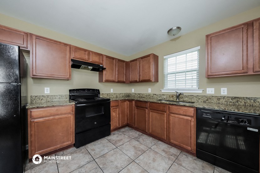 the kitchen has granite counter tops and black appliances