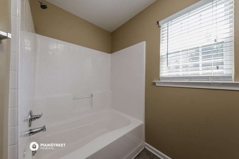 the master bathroom has a large tub and a shower and a window