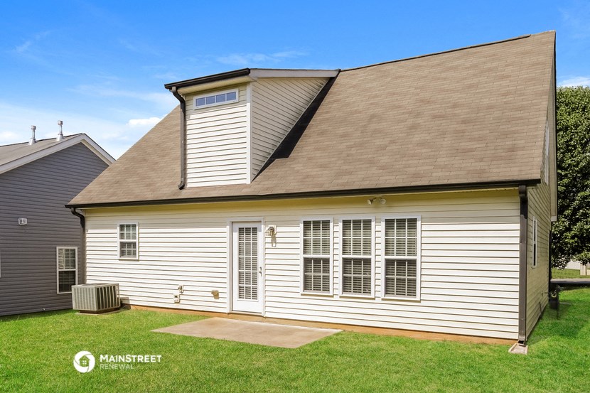 a side view of a white house with white siding and a brown roof