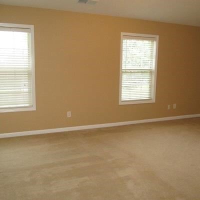 a living room with two windows and a carpet