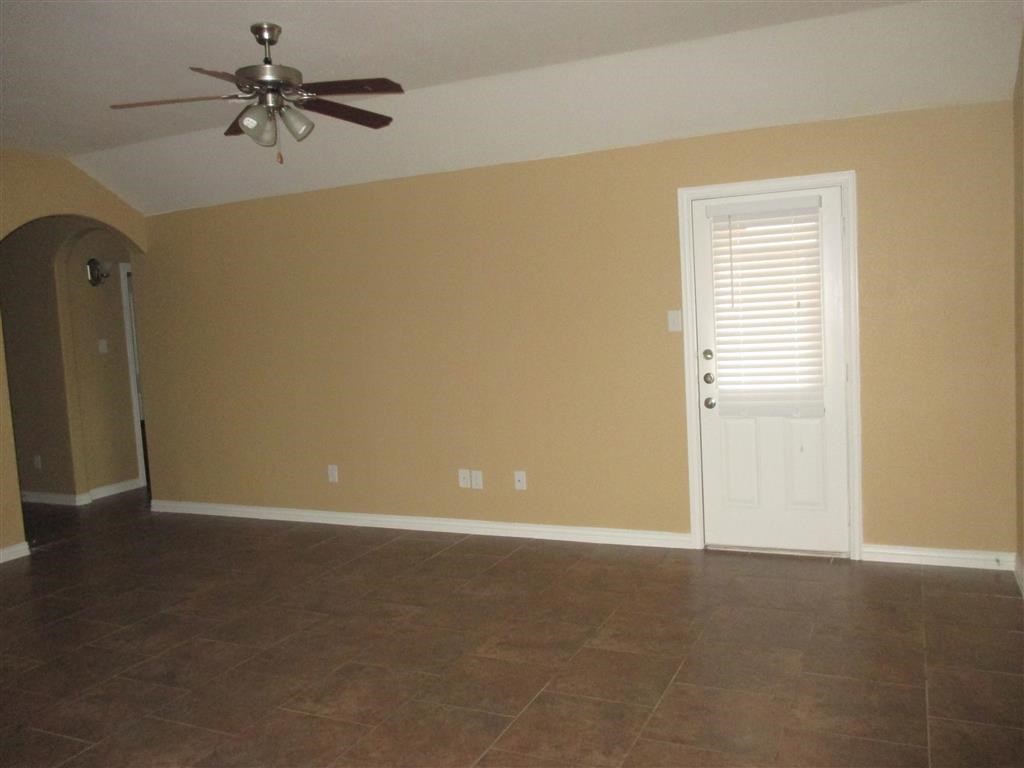 an empty living room with a ceiling fan and a door