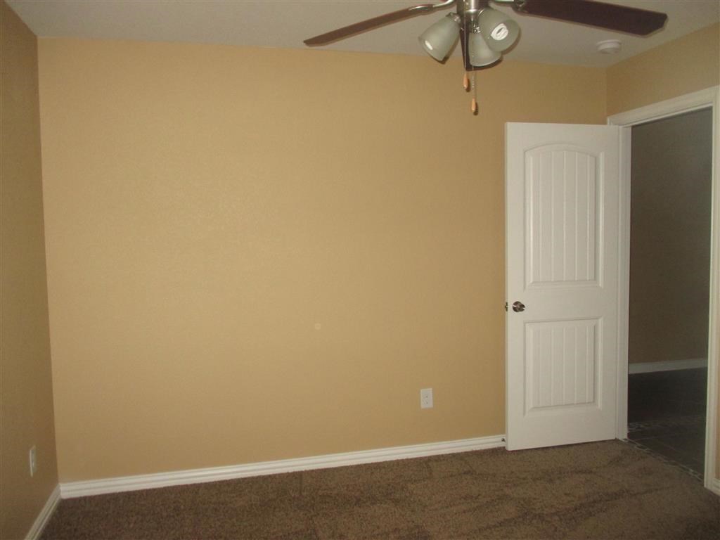 a empty room with a ceiling fan and a door