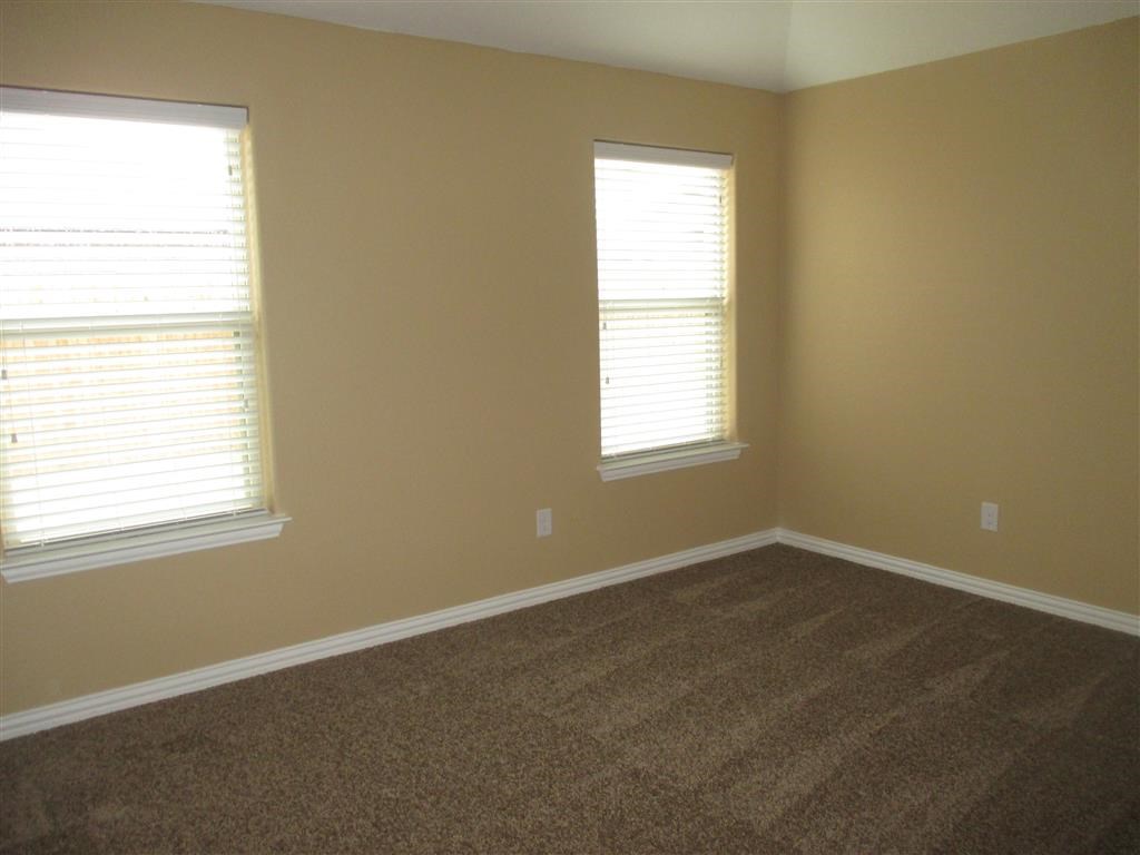 a room with carpet and two windows