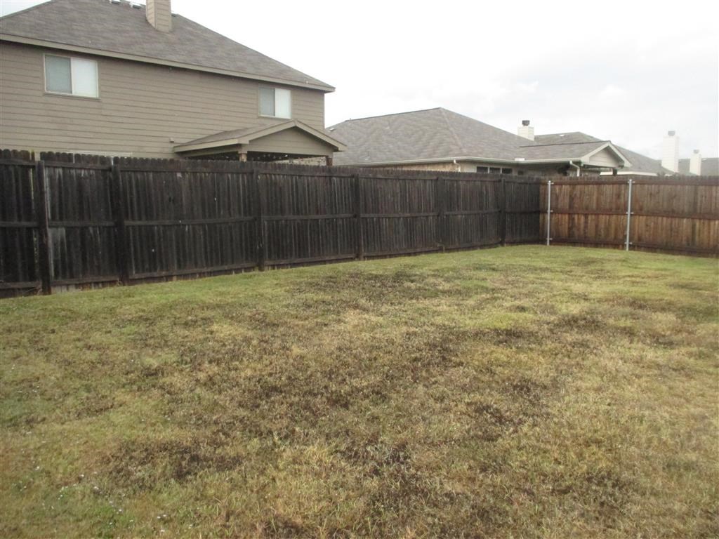 a wooden fence in a backyard in front of a house