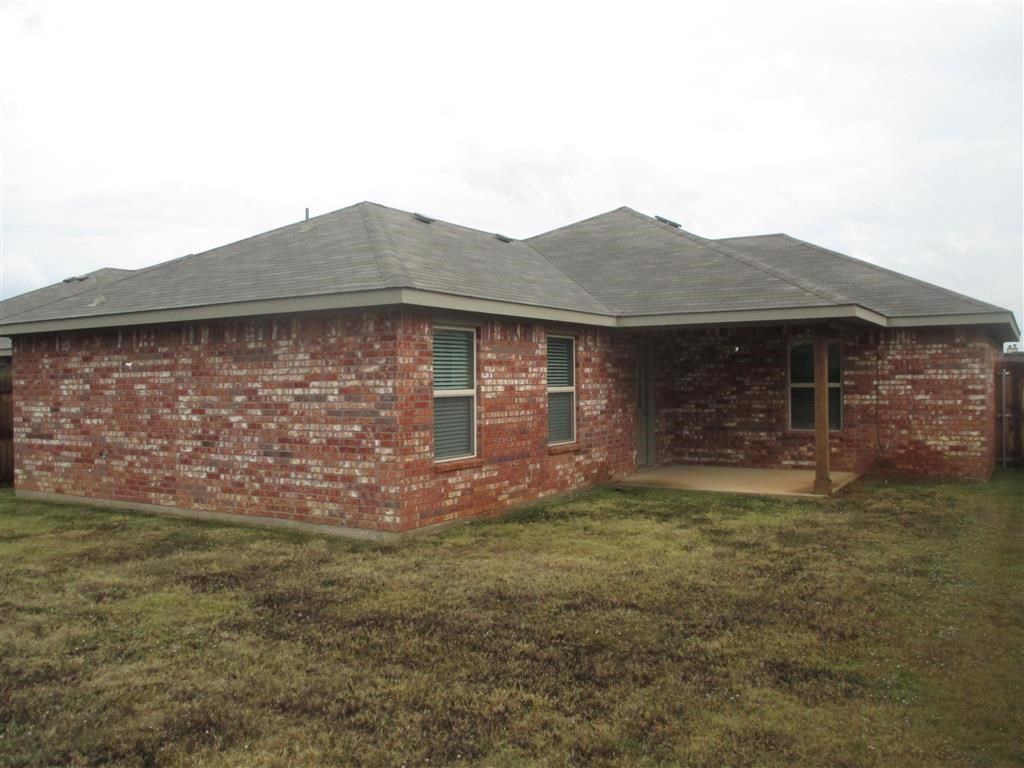 a brick house with a porch and a grassy yard