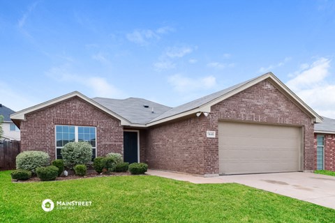 front view of a brick house with a yard and grass
