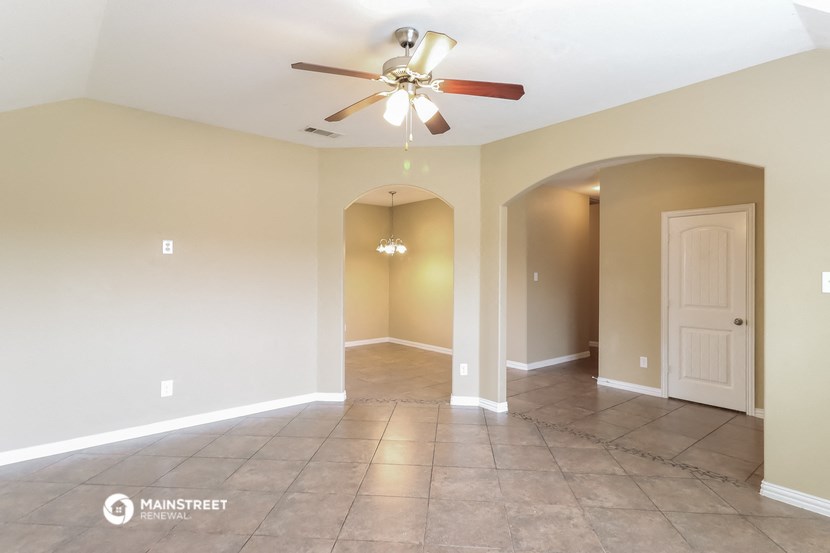 the spacious living room with tile flooring and a ceiling fan