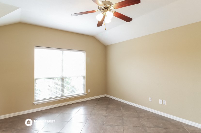 an empty living room with a ceiling fan and a window