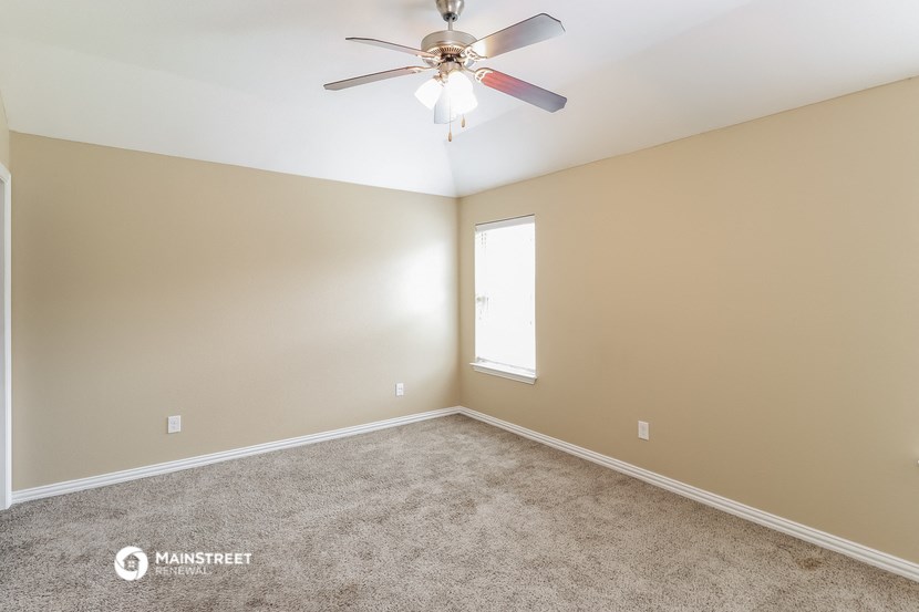 an empty room with a ceiling fan and a window