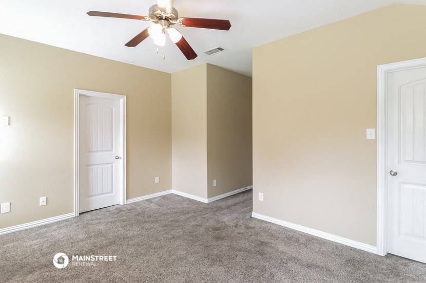 an empty room with a ceiling fan and a door