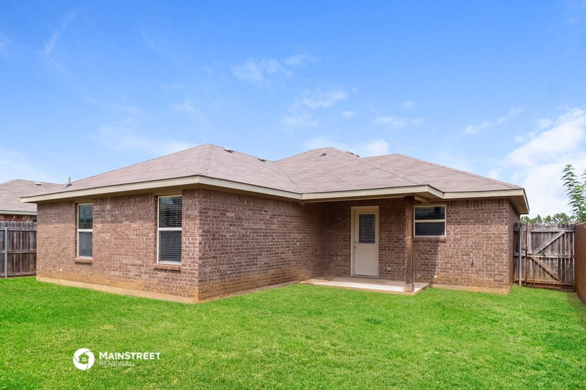 a small brick house with a lawn and a wooden fence