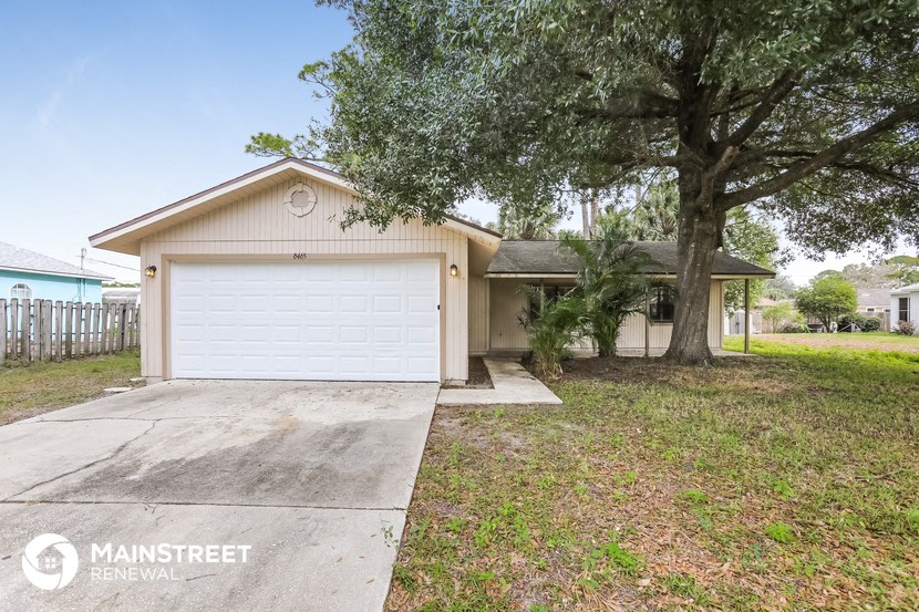 a small white house with a garage and a tree