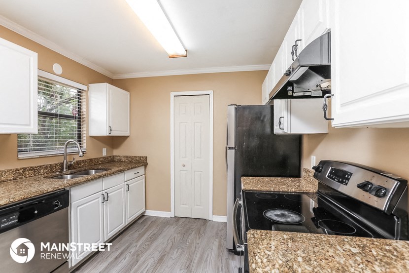 a kitchen with white cabinets and granite counter tops and black appliances