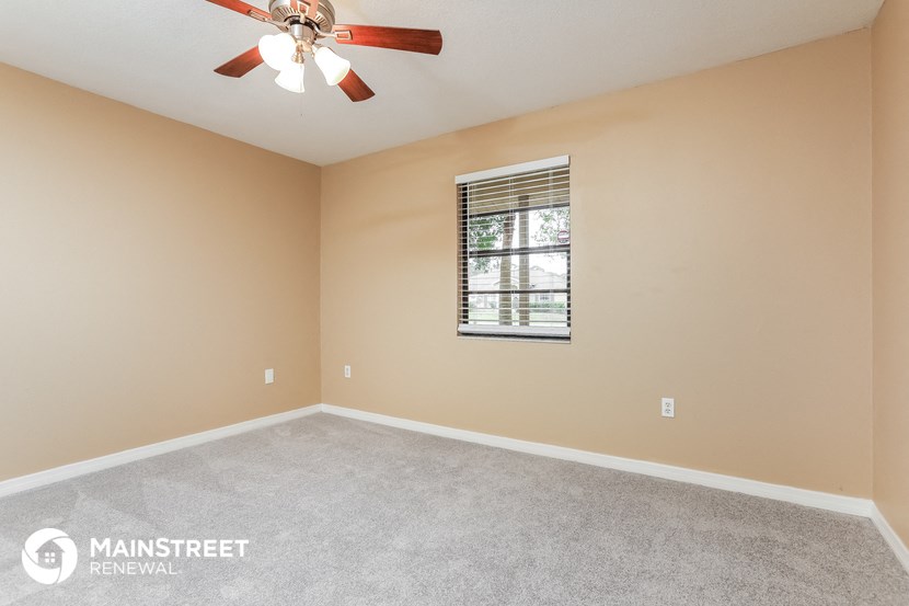 the master bedroom has a carpeted floor and a ceiling fan