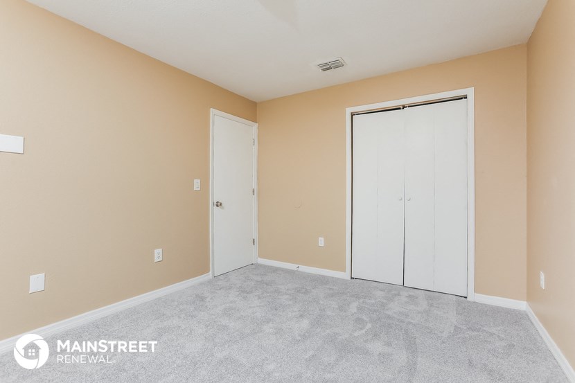 the living room of an apartment with a carpeted floor and two doors