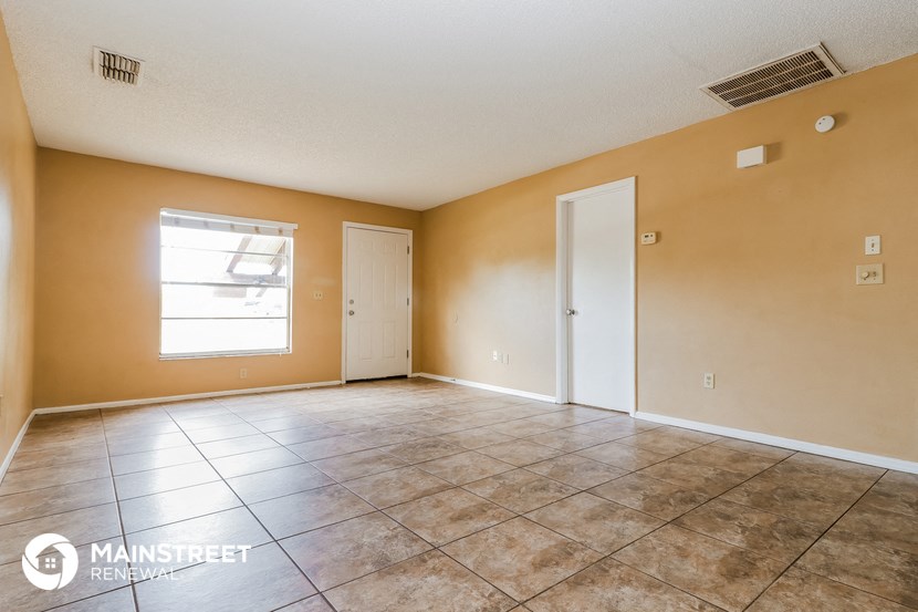 the living room of an empty house with tile floors and a window