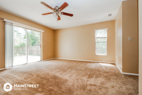 a living room with carpet and a ceiling fan