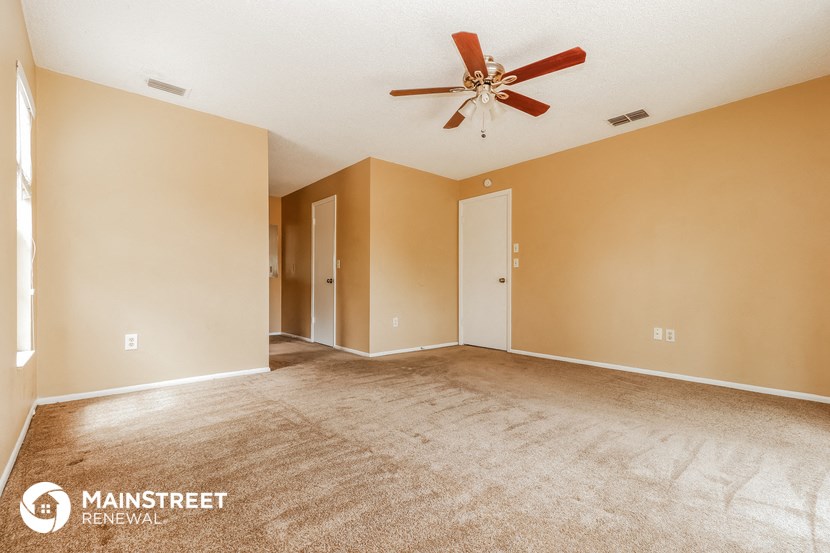 a living room with carpet and a ceiling fan