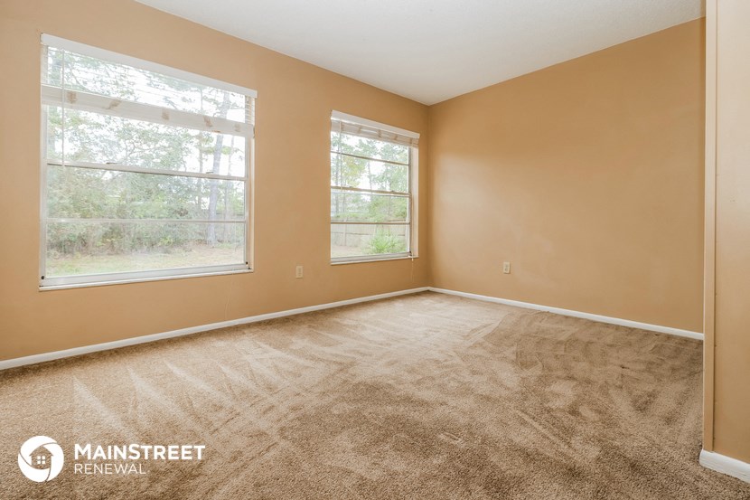 the living room of a home with carpet and a large window