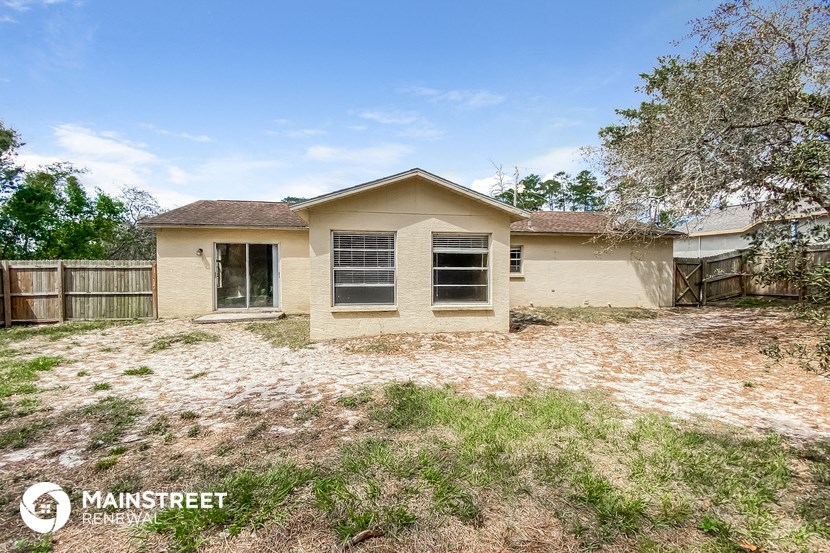 a small tan house with a yard and a fence