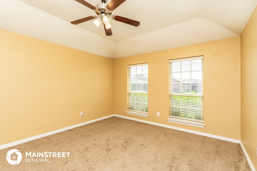 the master bedroom has a carpeted floor and a ceiling fan