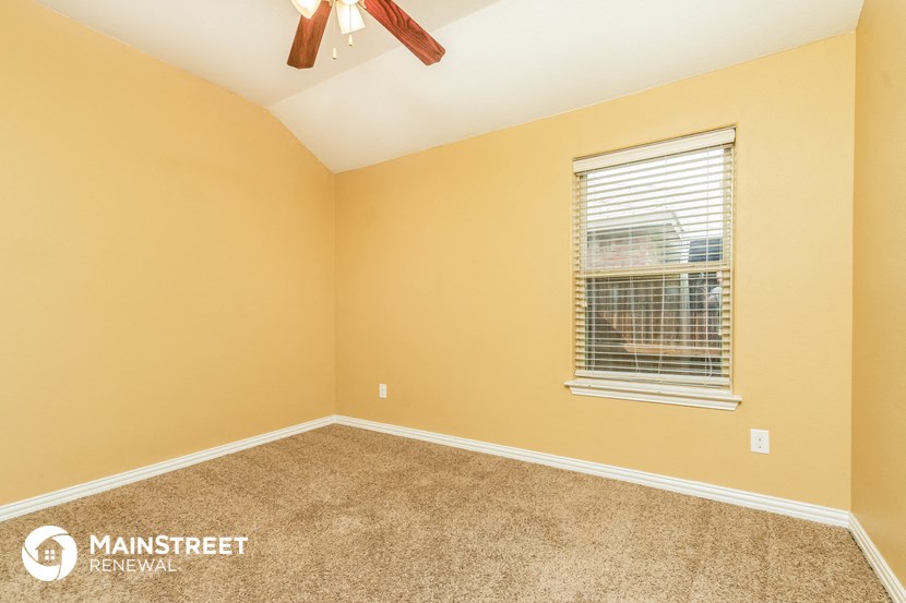 the bedroom of a home with a ceiling fan and a window