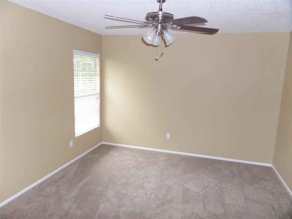 an empty living room with a ceiling fan