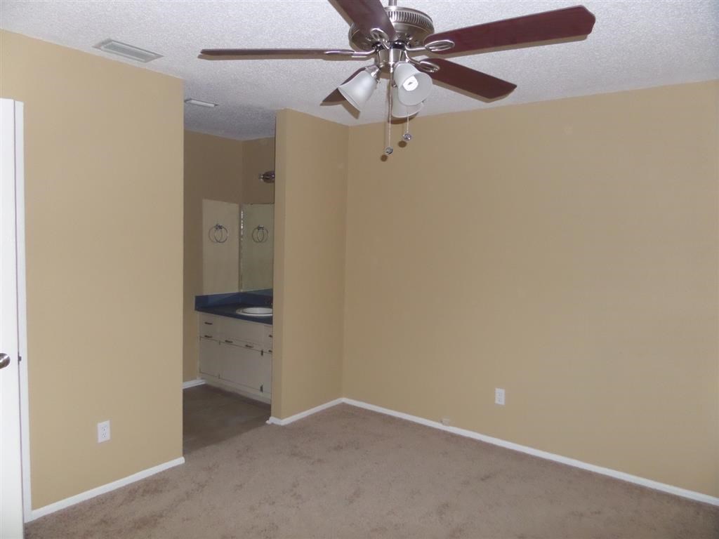 an empty room with a ceiling fan and a bathroom