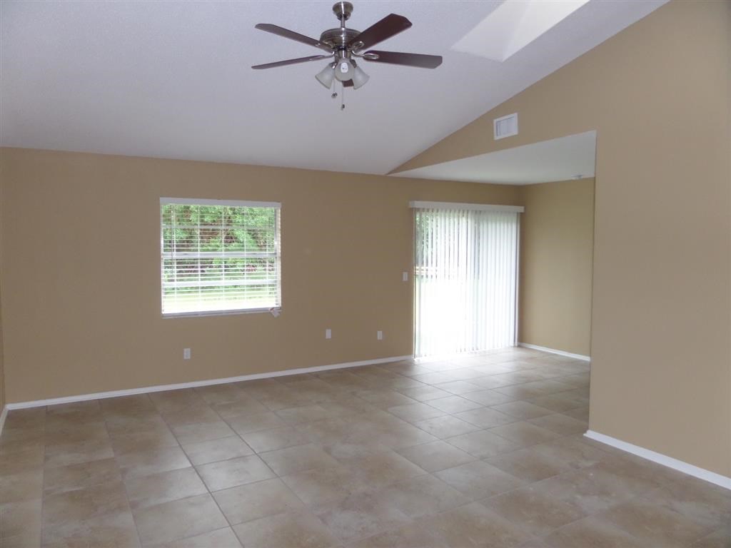 a large empty living room with a ceiling fan