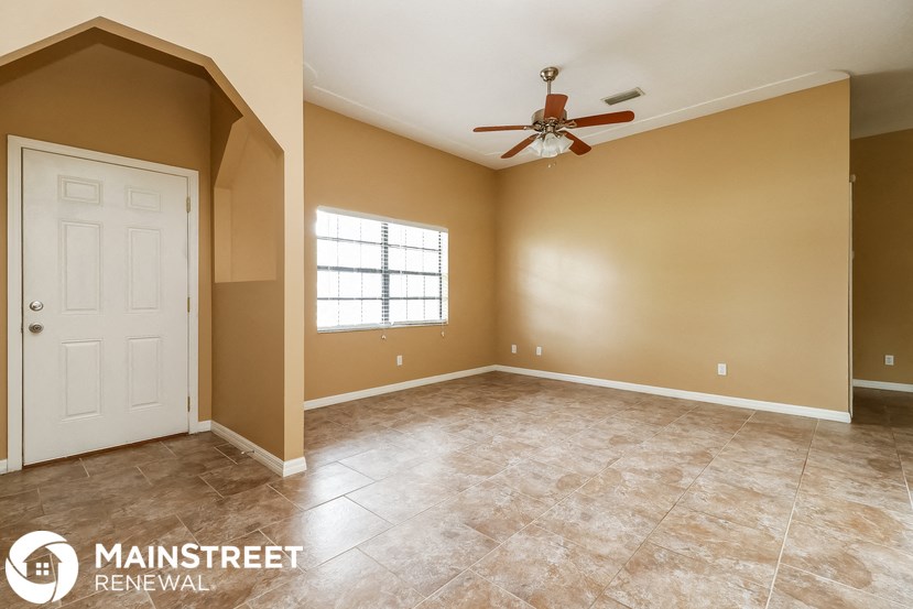 an empty living room with a ceiling fan and a white door