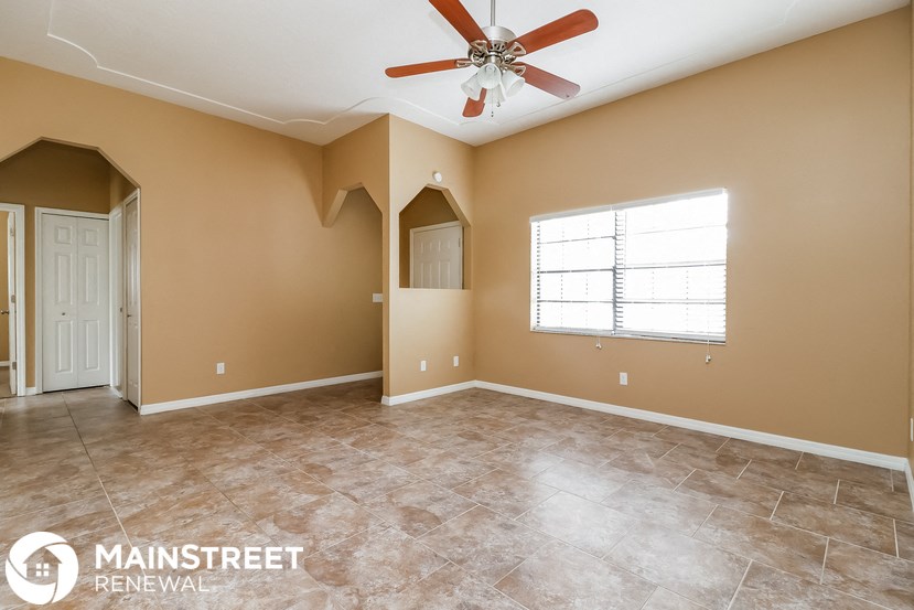 an empty living room with a ceiling fan and a window
