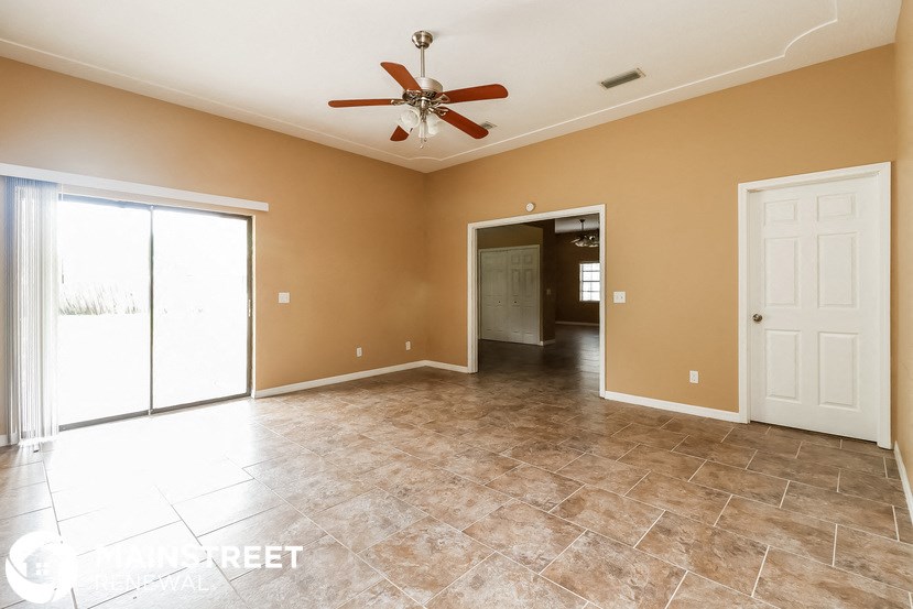 an empty living room with a ceiling fan and tile floor
