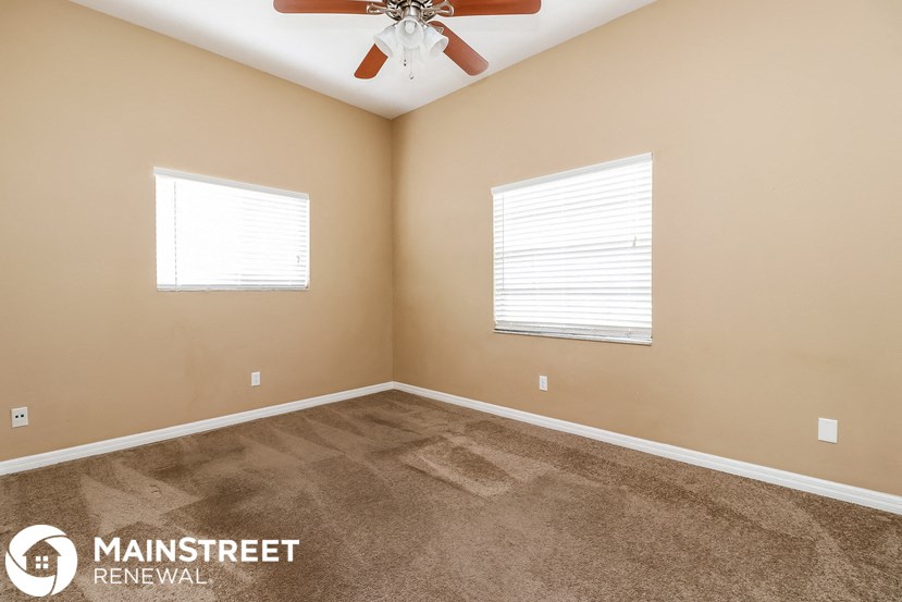 the master bedroom has a carpeted floor and a ceiling fan