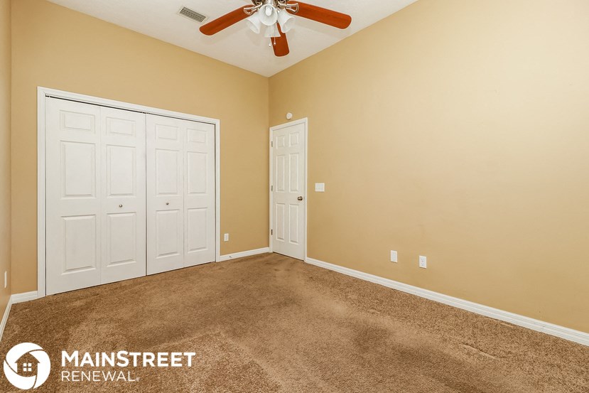 the master bedroom has a carpeted floor and a ceiling fan