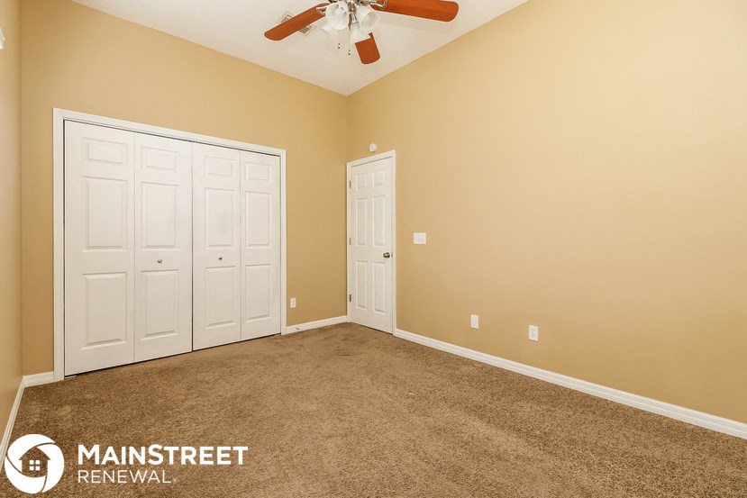 a carpeted room with two doors and a ceiling fan