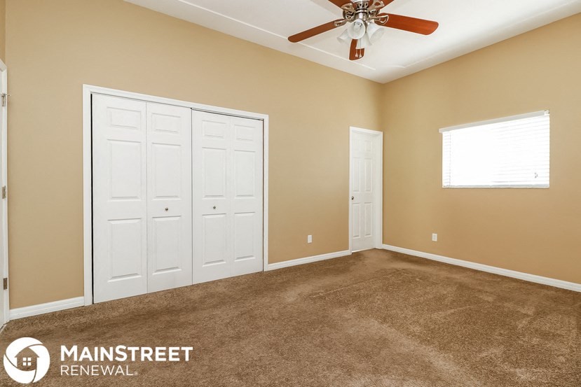 a carpeted room with two white doors and a ceiling fan