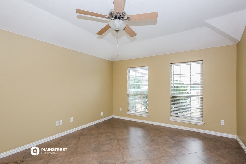 an empty living room with a ceiling fan and windows