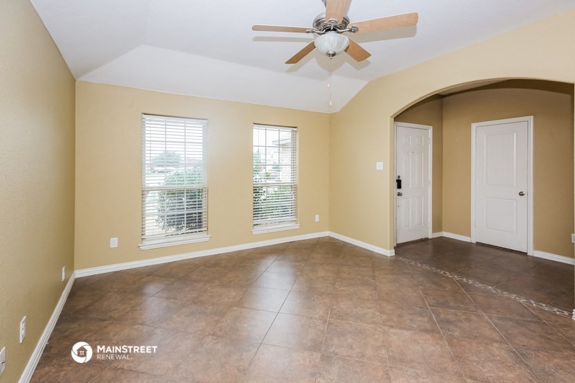 the spacious living room with ceiling fan and tile flooring