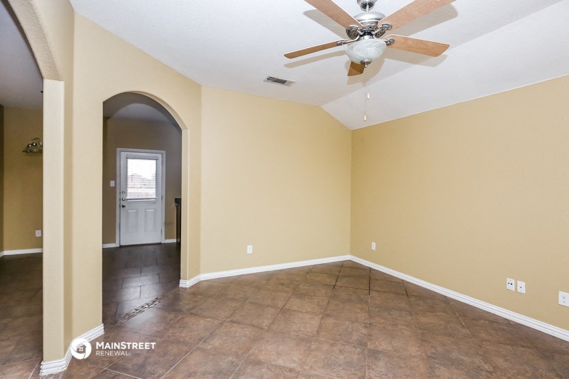 an empty living room with a ceiling fan