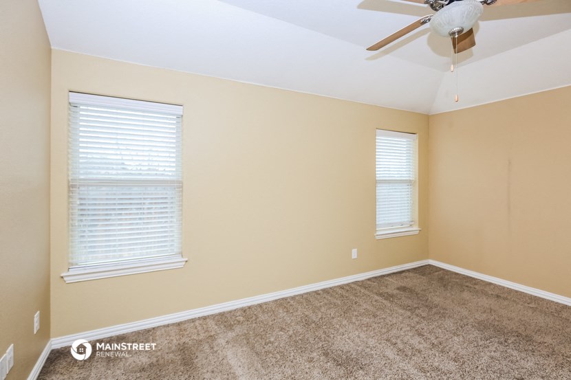 a bedroom with carpet and a ceiling fan and two windows