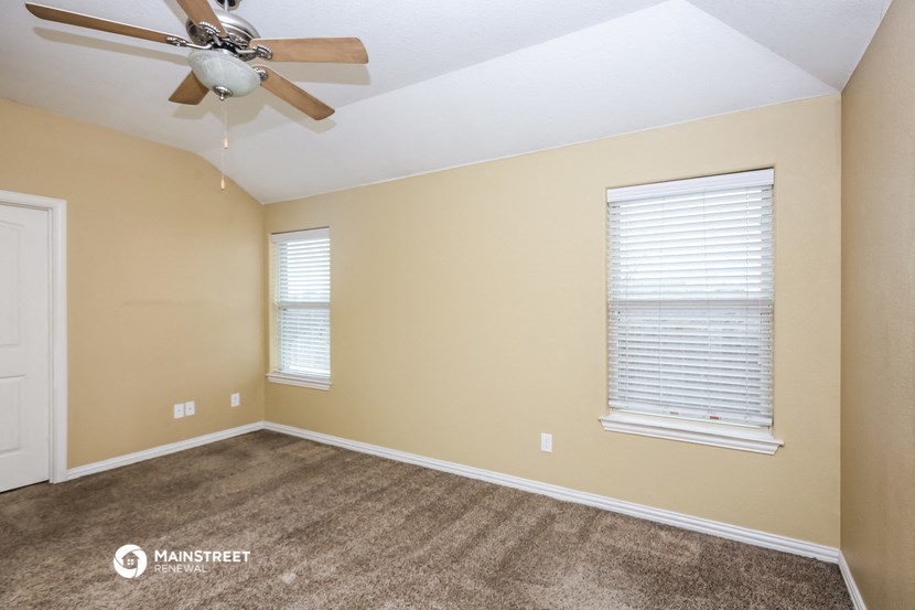 the upstairs bedroom with carpet and a ceiling fan